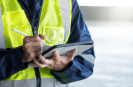 Person in yellow safety vest filling out compliance forms